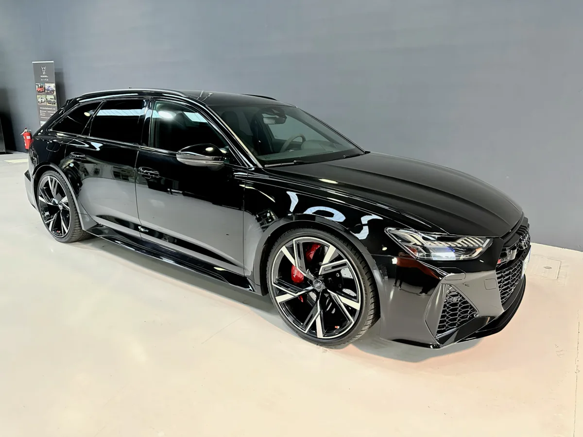 Side view of the Audi RS6 MY20 sporty estate in dark gray, alloy wheels and aggressive front splitter inside Exclusive Rent Italy Showroom.