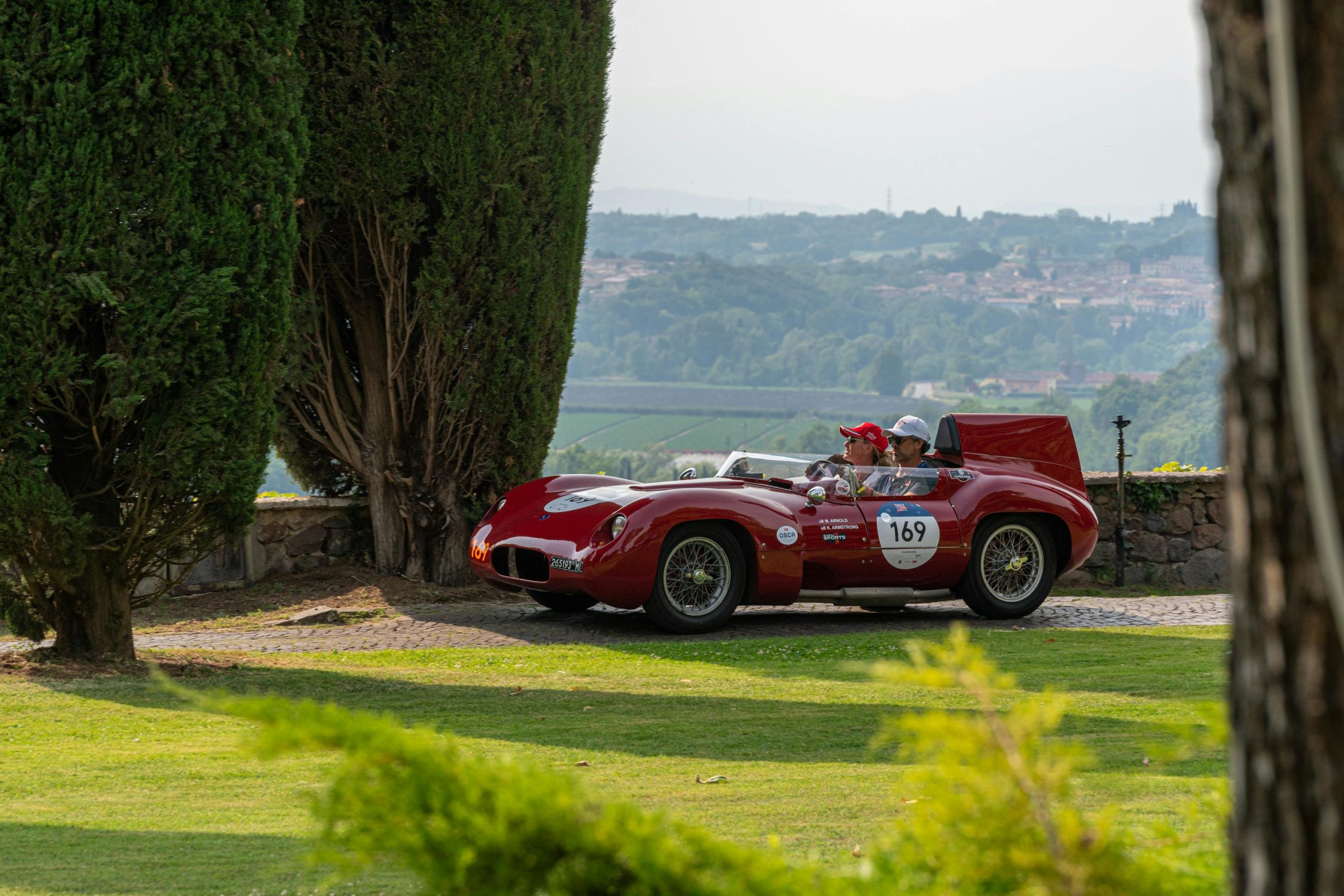Auto storica della 1000 Miglia in transito lungo un percorso panoramico italiano durante la rievocazione storica
